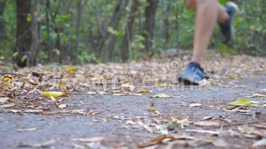 <strong>少年</strong>运动员在初秋森林中沿着小径奔跑的雄脚。 <strong>强</strong>壮运动员的腿沿着小径慢跑